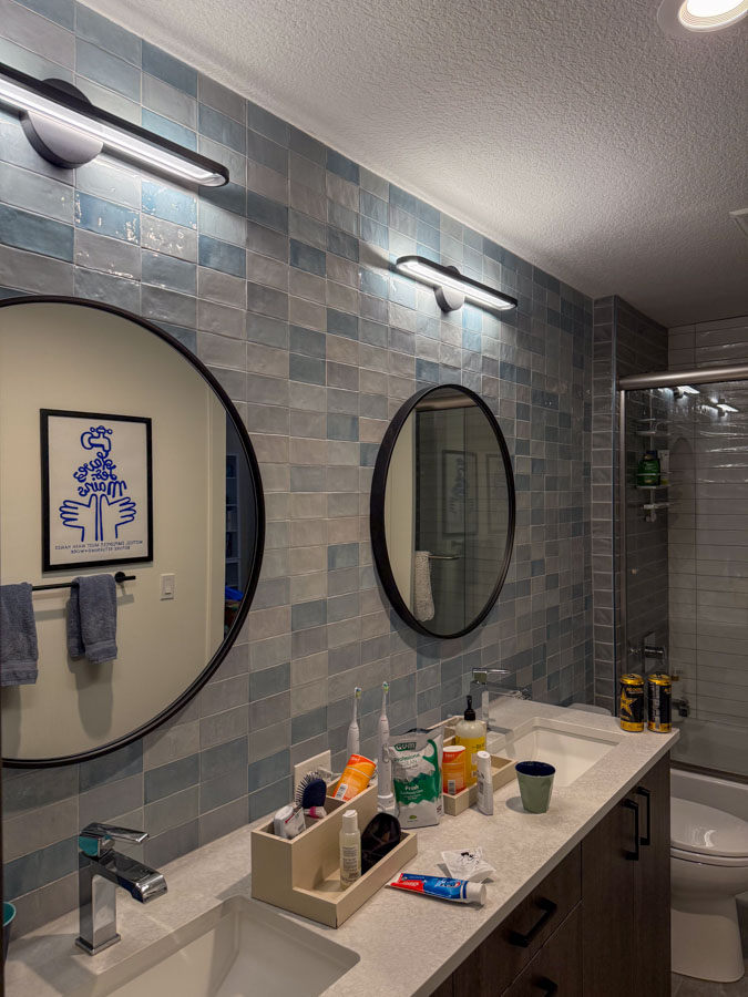 A modern bathroom vanity with a clean countertop, organized toiletries, and blue-toned wall tiles for a fresh aesthetic.